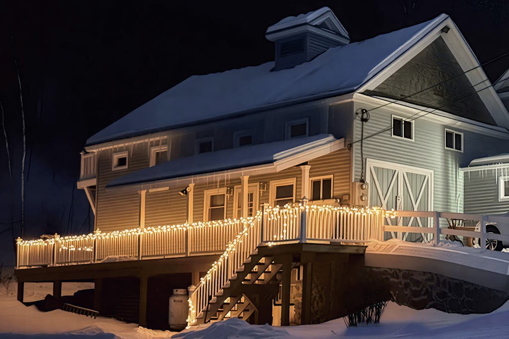 Carriage House exterior at night with string lights on the snow