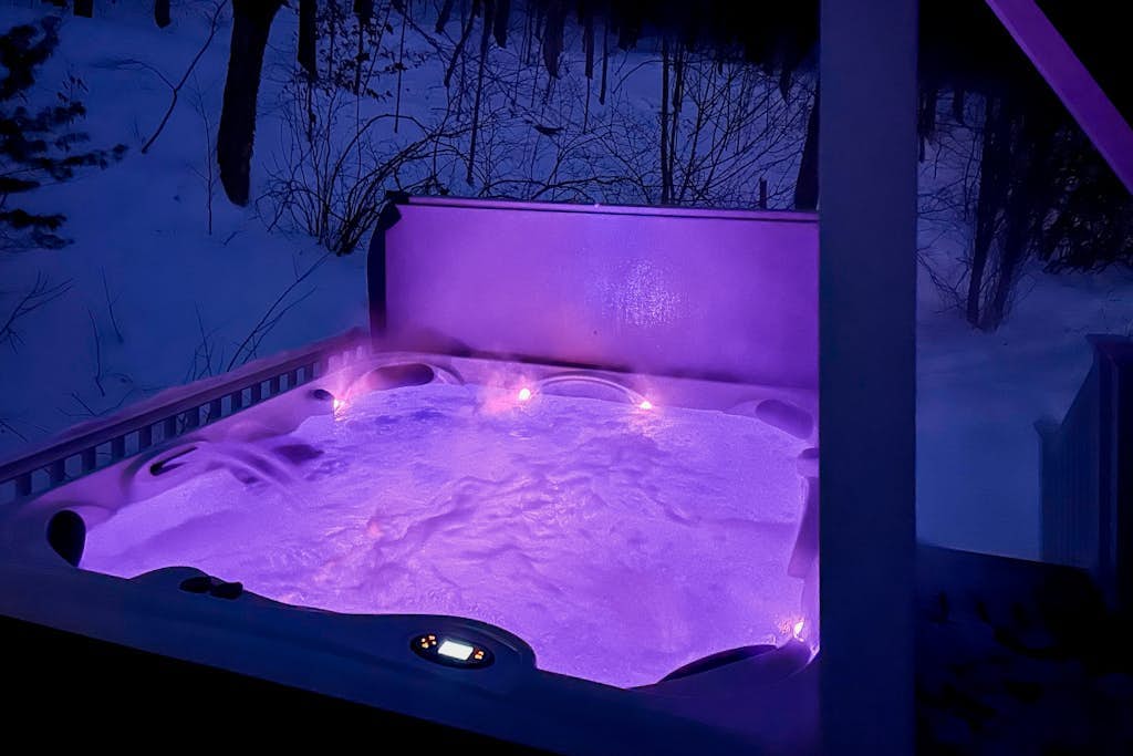 Hot tub glowing purple against the snow at night